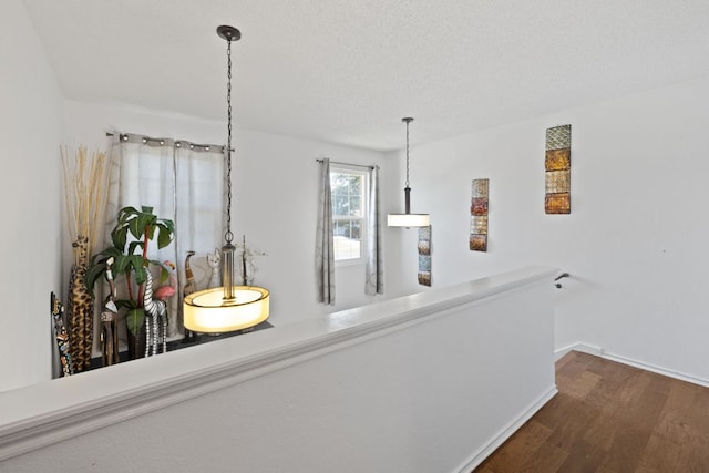 hall with dark wood finished floors, a textured ceiling, and baseboards