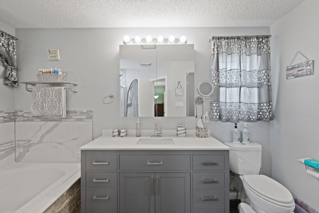 bathroom with a bathing tub, a textured ceiling, vanity, and toilet