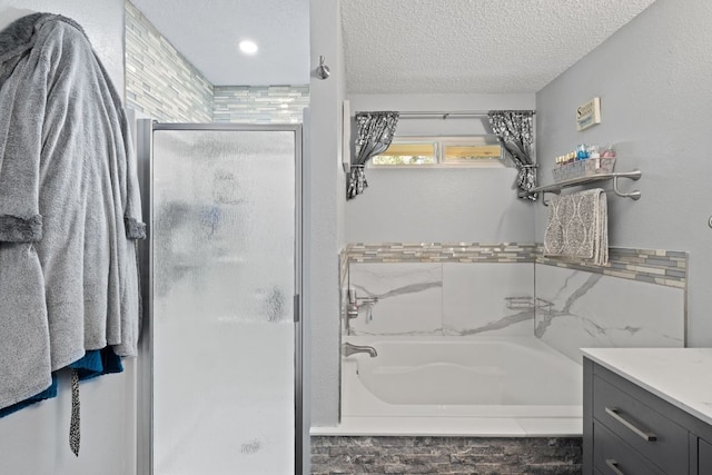 bathroom featuring a bathing tub, a shower stall, a textured ceiling, and vanity