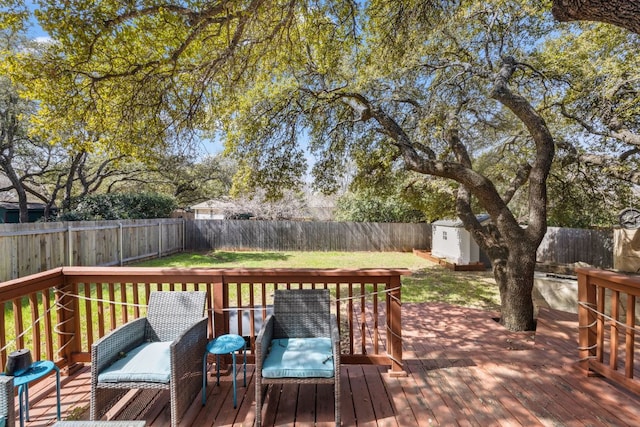 wooden deck featuring a storage unit, an outdoor structure, a fenced backyard, and a lawn