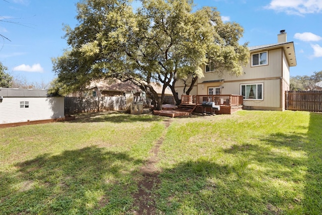 view of yard with a deck, an outbuilding, and a fenced backyard