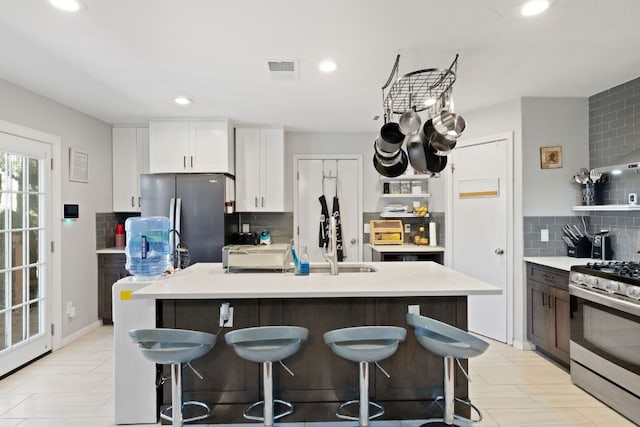 16700 Black Kettle Dr, Leander, TX 78641 - kitchen featuring an island with sink, stainless steel appliances, a kitchen breakfast bar, light countertops, and decorative backsplash