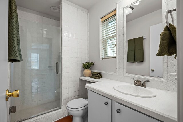 bathroom with toilet, a stall shower, and vanity