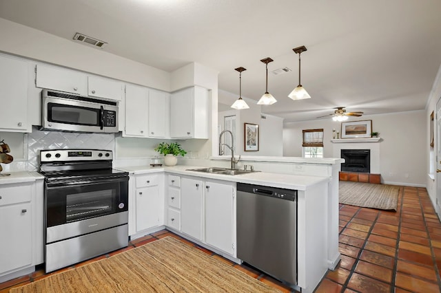 kitchen featuring a peninsula, a sink, visible vents, open floor plan, and appliances with stainless steel finishes