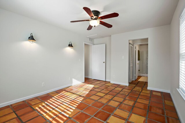 unfurnished bedroom with attic access, baseboards, and a ceiling fan