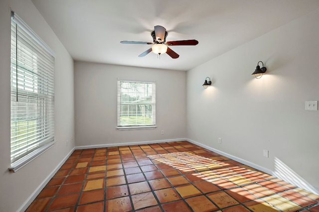 tiled spare room with baseboards and a ceiling fan