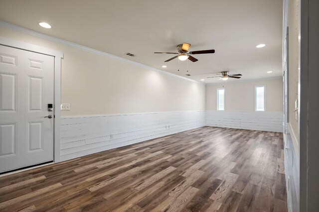 spare room with wainscoting, crown molding, visible vents, and wood finished floors