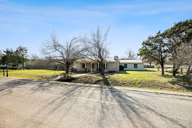 view of front of home featuring fence, a chimney, and a front lawn