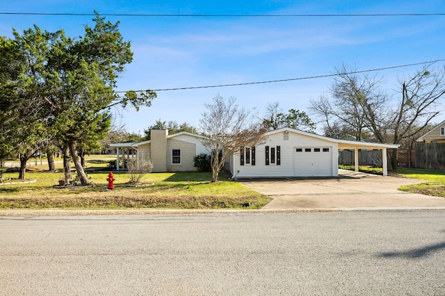 view of front of property with a garage, fence, concrete driveway, a carport, and a front lawn