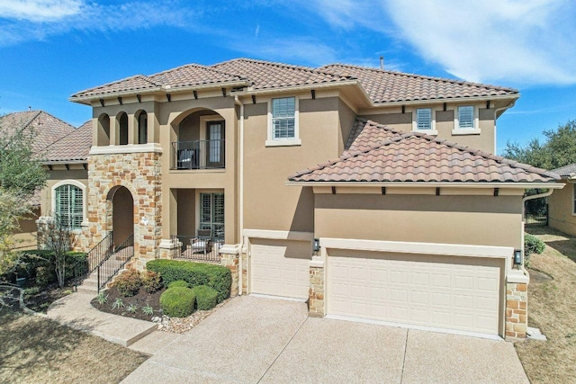 mediterranean / spanish-style house with a tile roof, concrete driveway, stone siding, and stucco siding