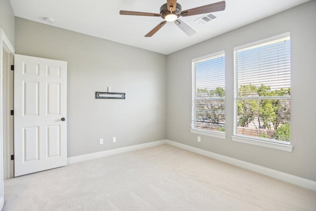 spare room with visible vents, light colored carpet, a ceiling fan, and baseboards