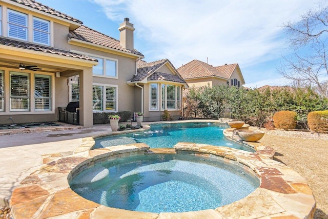 view of swimming pool featuring a pool with connected hot tub, a ceiling fan, and a patio