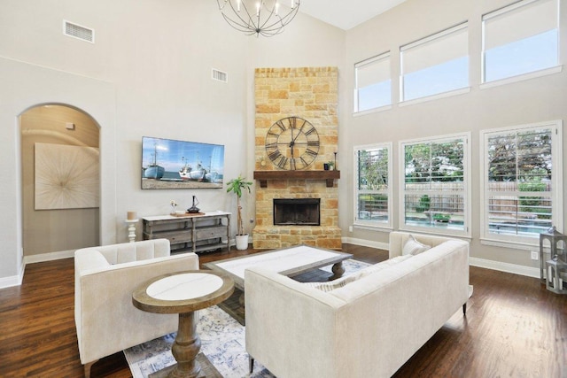 living room with visible vents, high vaulted ceiling, a stone fireplace, and dark wood-style flooring