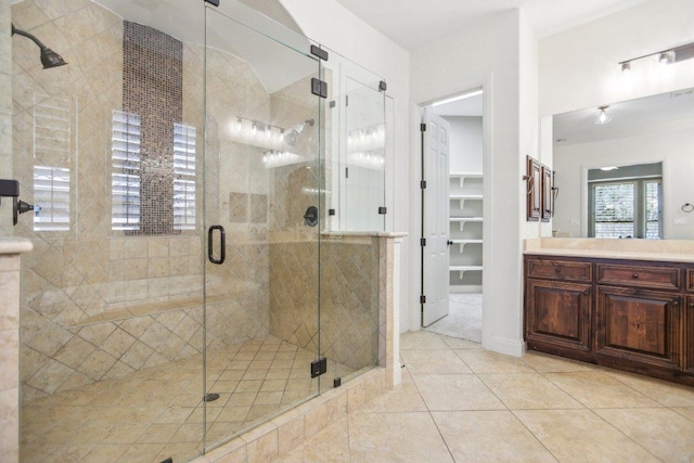 bathroom with tile patterned flooring, a spacious closet, vanity, and a stall shower