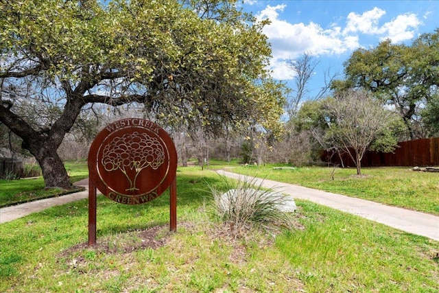 community / neighborhood sign with a yard and fence