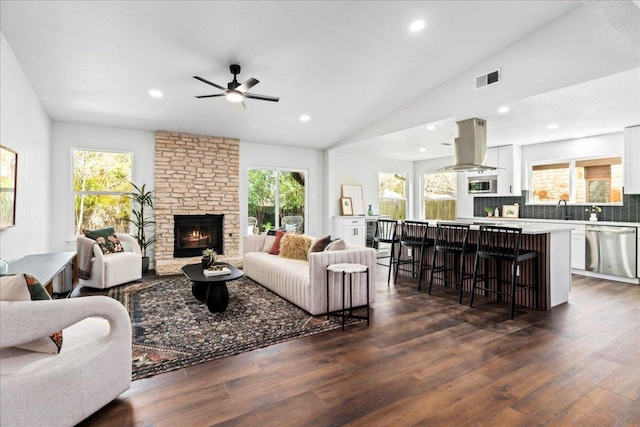 living room with dark wood-style floors, a fireplace, lofted ceiling, and a healthy amount of sunlight