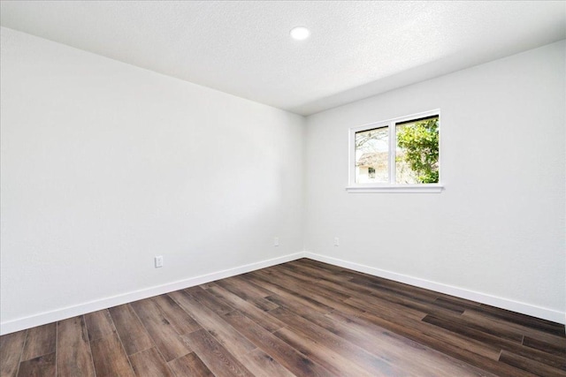 spare room featuring a textured ceiling, dark wood finished floors, and baseboards