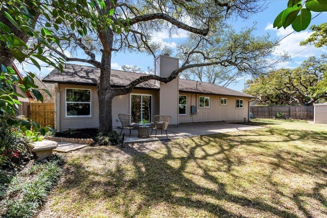 rear view of house featuring a patio, a chimney, and fence