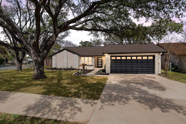 mid-century modern home with a garage, concrete driveway, a front lawn, and stone siding