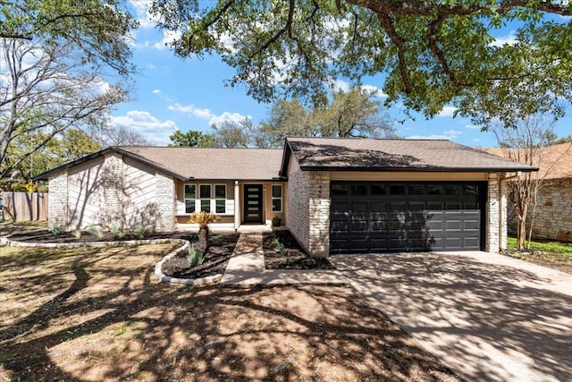 view of front of home featuring driveway, a garage, stone siding, and fence