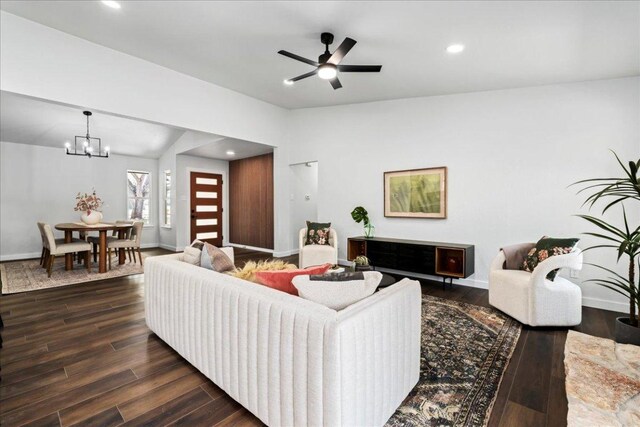 living room featuring dark wood-style flooring, a chandelier, baseboards, lofted ceiling, and recessed lighting