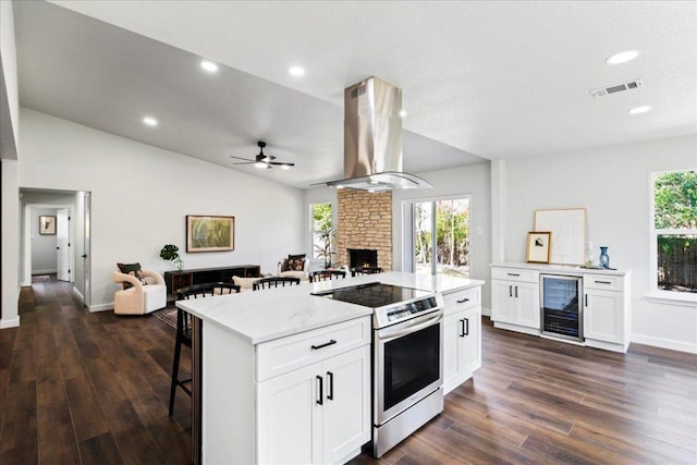 kitchen featuring beverage cooler, visible vents, island range hood, open floor plan, and stainless steel range with electric cooktop