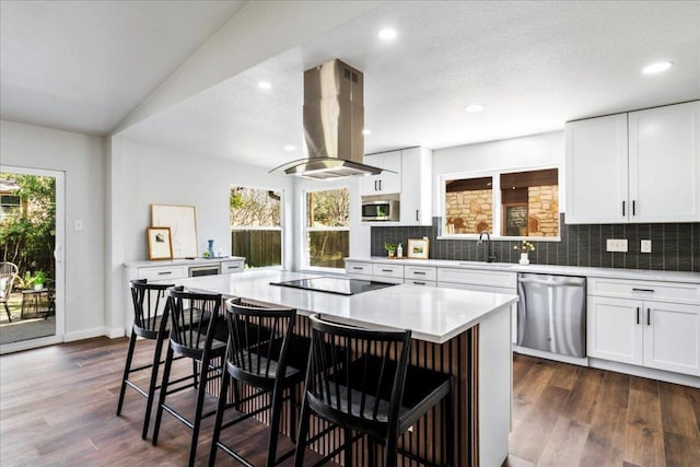 kitchen with a breakfast bar area, a sink, appliances with stainless steel finishes, tasteful backsplash, and island exhaust hood