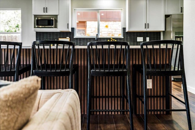 kitchen featuring stainless steel microwave, decorative backsplash, and wood finished floors