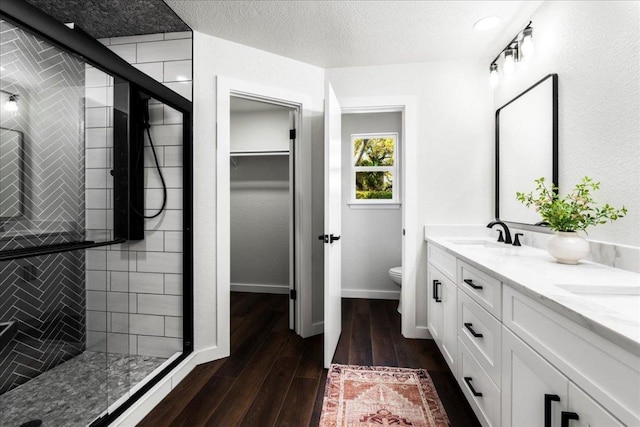 bathroom with a sink, a shower stall, toilet, and wood finished floors