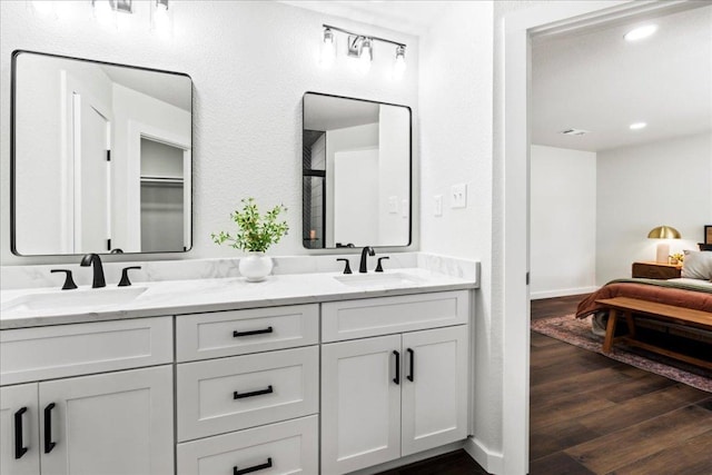 bathroom with wood finished floors, double vanity, recessed lighting, and baseboards