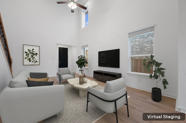 living room with ceiling fan, stairs, light wood-style flooring, and baseboards