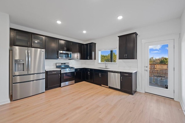 kitchen featuring a sink, stainless steel appliances, light countertops, light wood-style floors, and backsplash