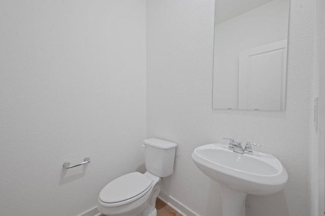 half bath featuring toilet and baseboards