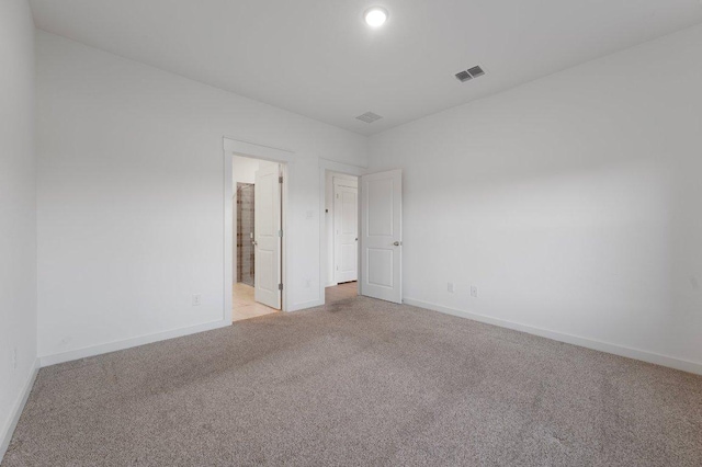 empty room featuring light carpet, baseboards, and visible vents