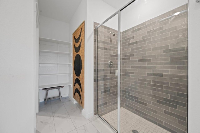 bathroom with marble finish floor, a spacious closet, and a shower stall