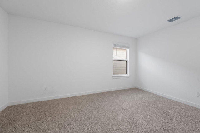 spare room with carpet flooring, visible vents, and baseboards