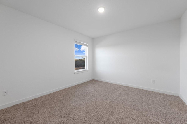 spare room featuring carpet and baseboards