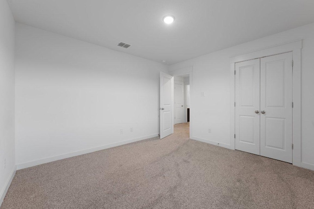 unfurnished bedroom with a closet, carpet flooring, visible vents, and baseboards