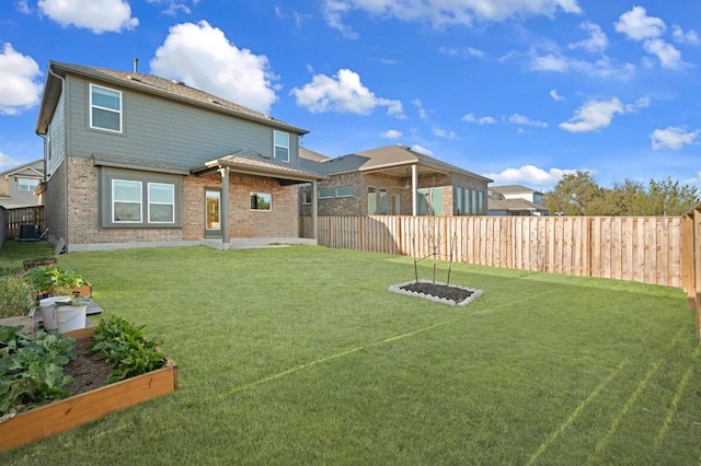 exterior space featuring a yard, central AC, brick siding, and a vegetable garden