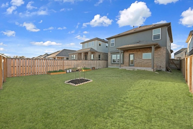 rear view of house with a fenced backyard, a lawn, and brick siding