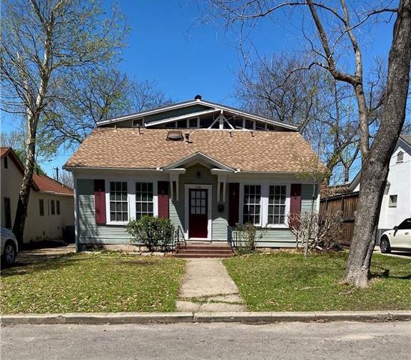 bungalow-style house featuring roof with shingles and a front yard