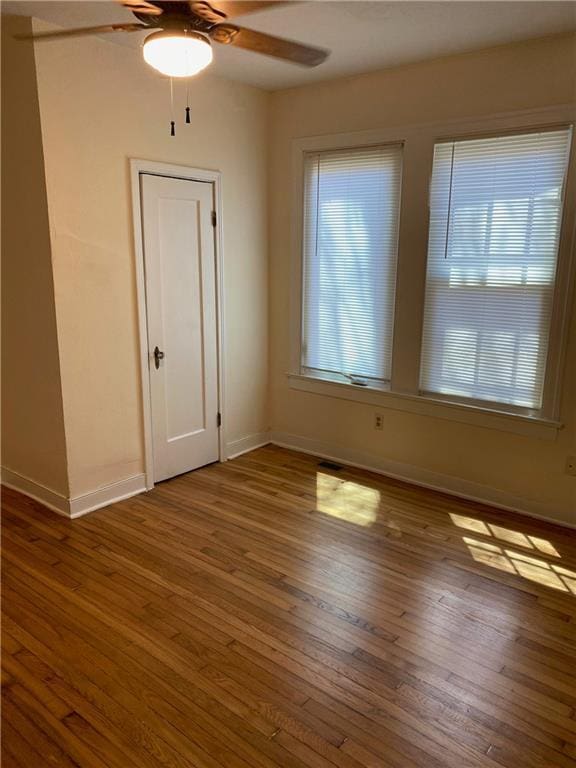 spare room featuring wood finished floors, a ceiling fan, and baseboards