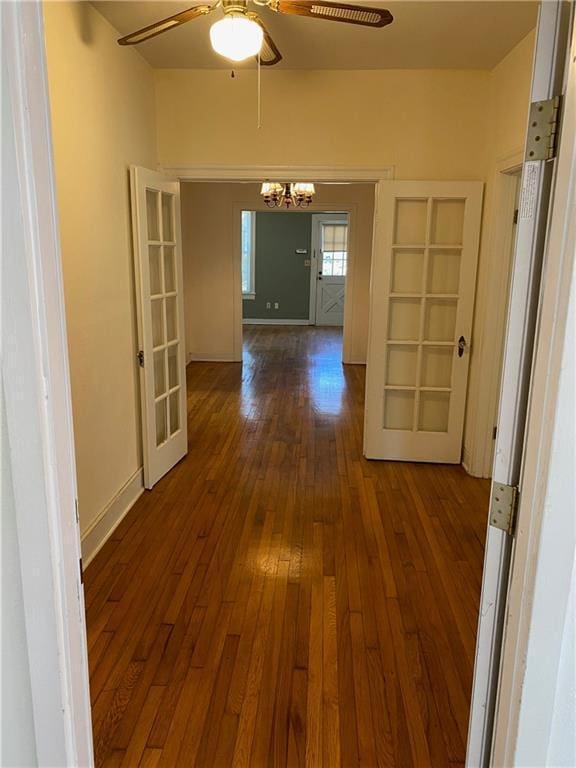 corridor with an inviting chandelier, dark wood finished floors, and baseboards