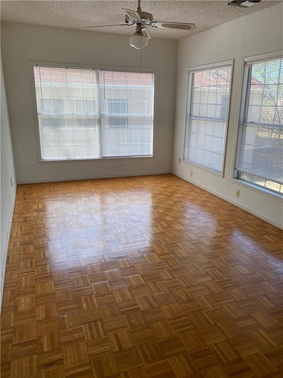 empty room with a textured ceiling, ceiling fan, and a wealth of natural light