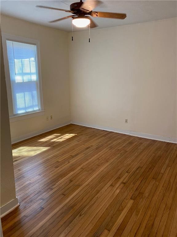 unfurnished room featuring hardwood / wood-style flooring, baseboards, and a ceiling fan