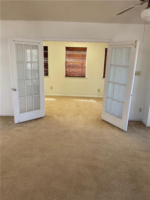 carpeted empty room with ceiling fan, french doors, and baseboards