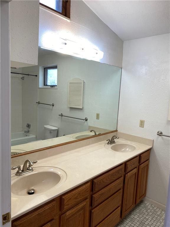 bathroom with double vanity, a sink, and toilet