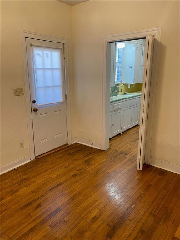 doorway with a sink, dark wood finished floors, and baseboards