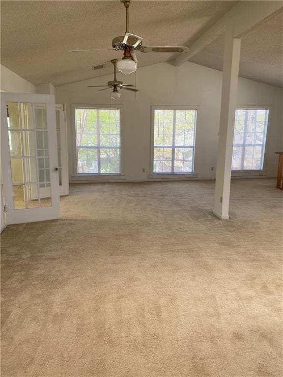 carpeted empty room with visible vents, a ceiling fan, vaulted ceiling, and a textured ceiling