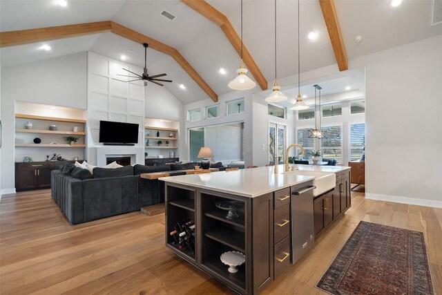 kitchen with light wood finished floors, beam ceiling, open shelves, and a sink